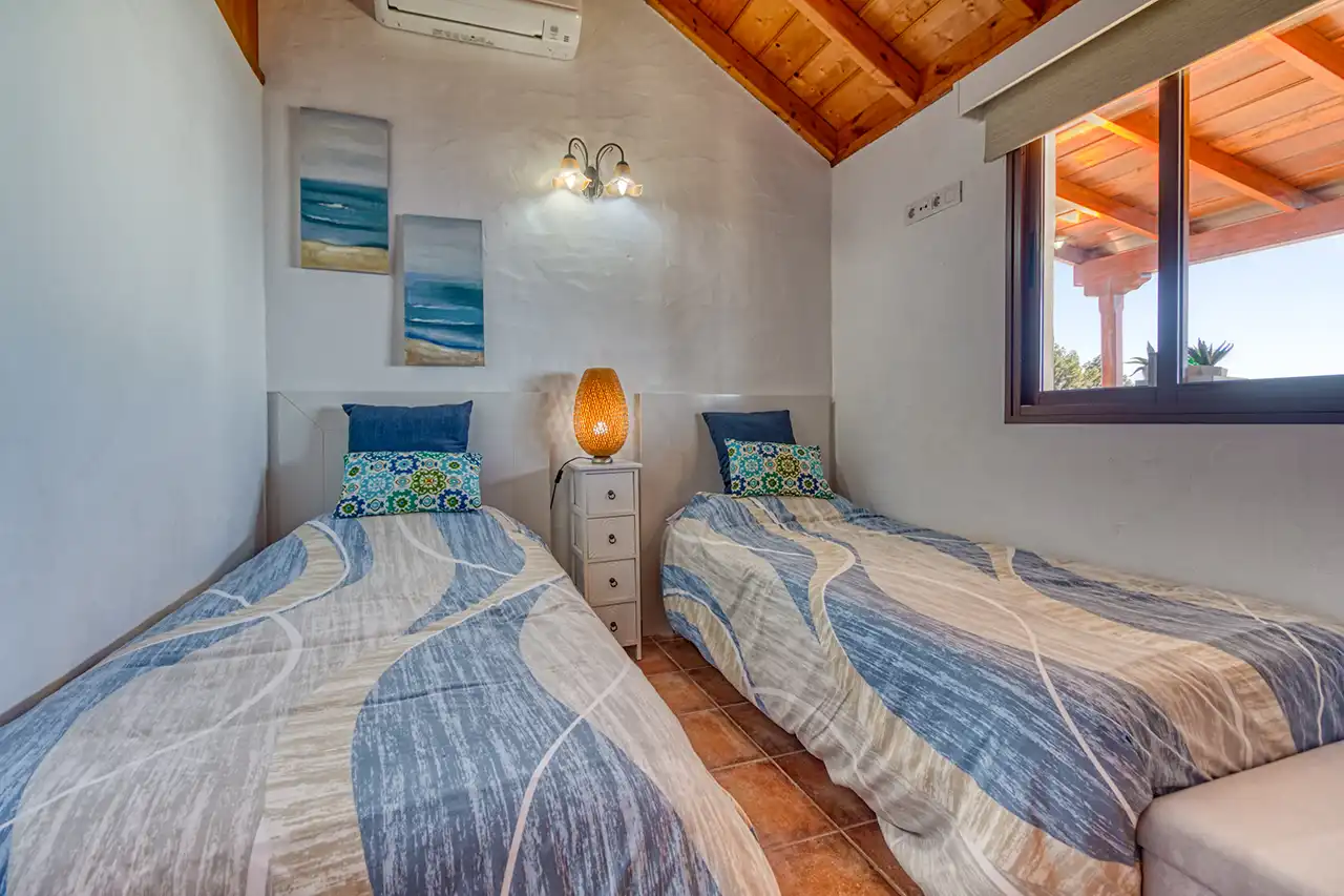 Villa Atardecer – Segundo dormitorio con camas individuales y ventana hacia la terraza